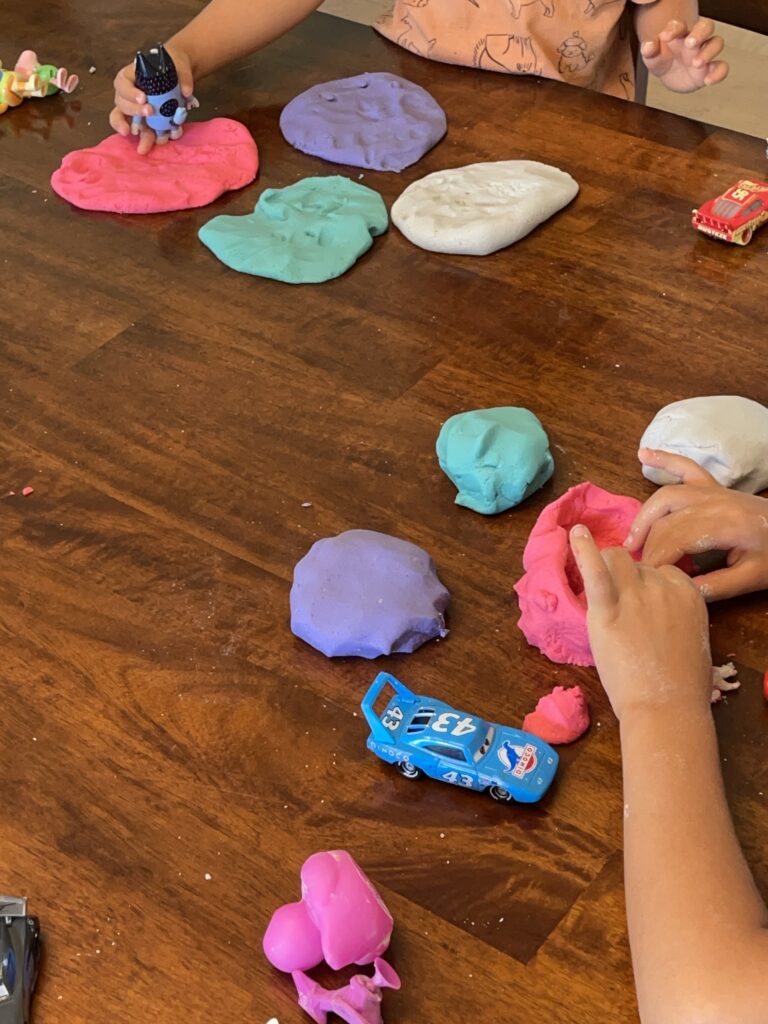 natural homemade playdough recipe made by kids for the hero · child hands scooping flour for no-cook playdough